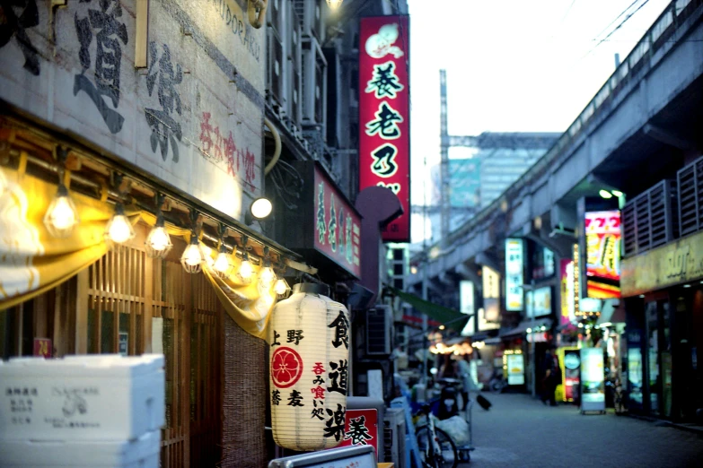 a narrow street in an asian country with lights and lanterns strung over