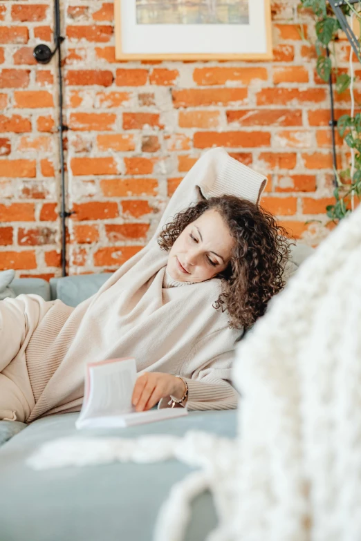 a woman is laying down on a couch reading