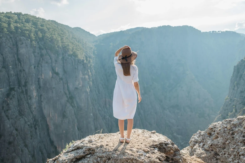 woman standing at the top of a mountain with view of canyon below