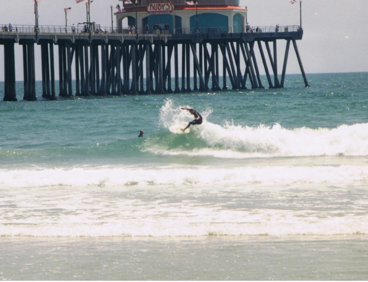 a surfer is surfing in front of the pier