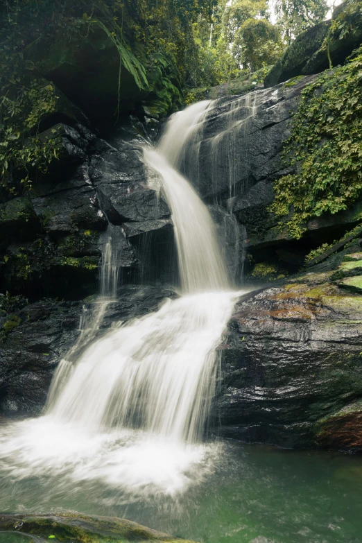 a water fall at a jungle location, with a rock cliff in the background