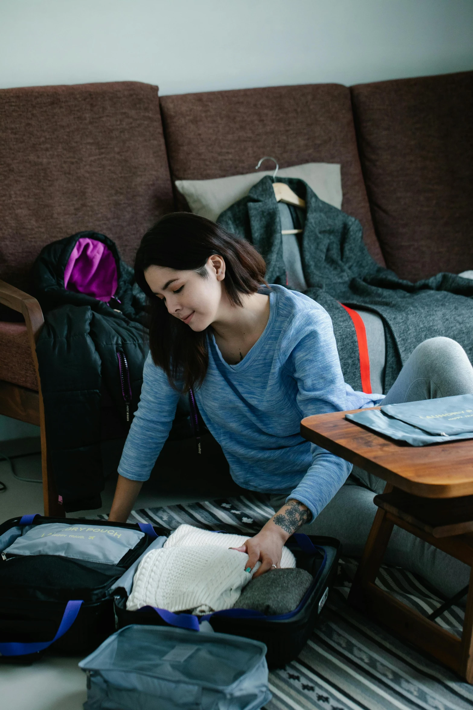 a woman packing luggage on the floor of her apartment