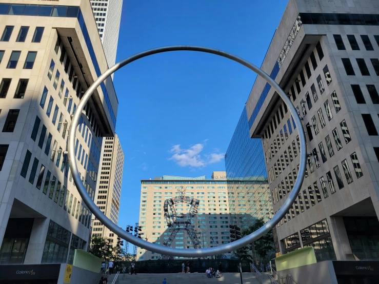 a circular statue in front of tall buildings