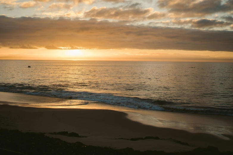 a lone sailboat is anchored on the beach during sunset