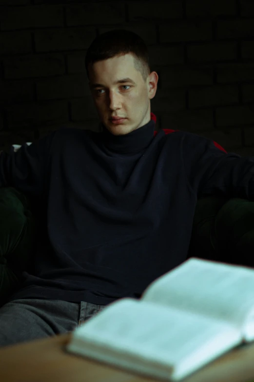 a young man is sitting on a couch reading a book