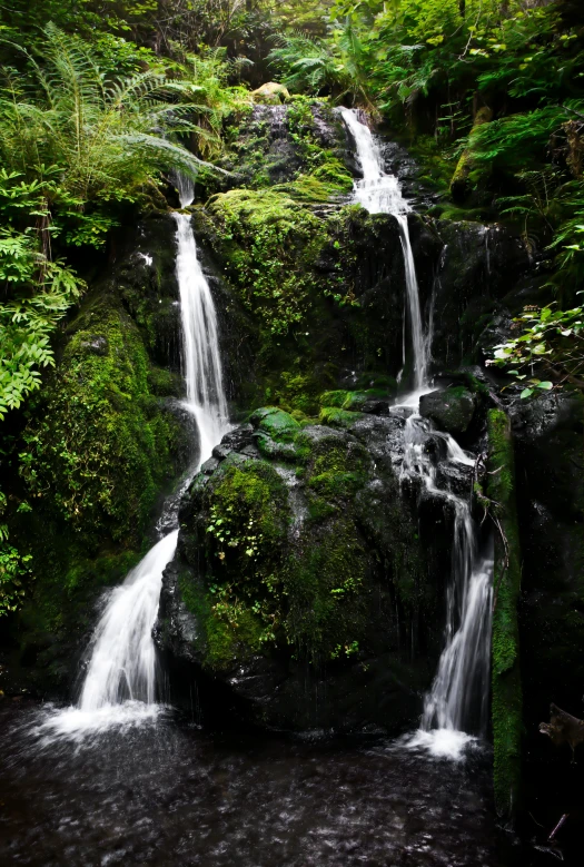 a small waterfall cascades into some deep green water