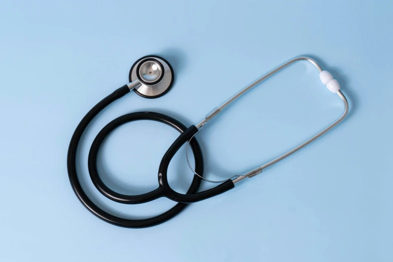 a stethoscope, an empty measuring cup and pills on a blue surface