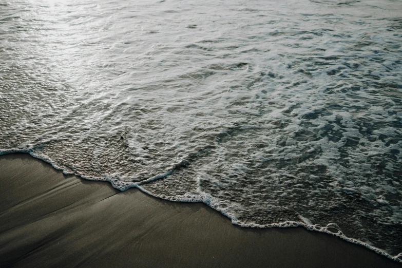 the surf comes in over the sandy beach