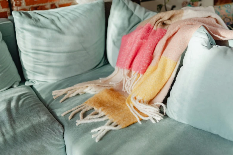 two multicolored blankets are laying on the back of a sofa