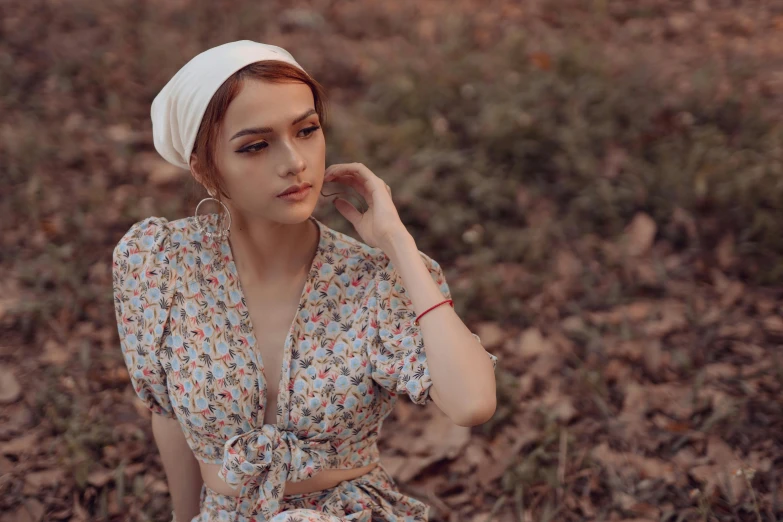 a girl is sitting down in a leafy field