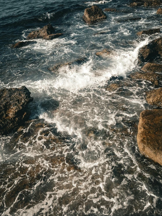 the waves wash up on the rocks on a cold day