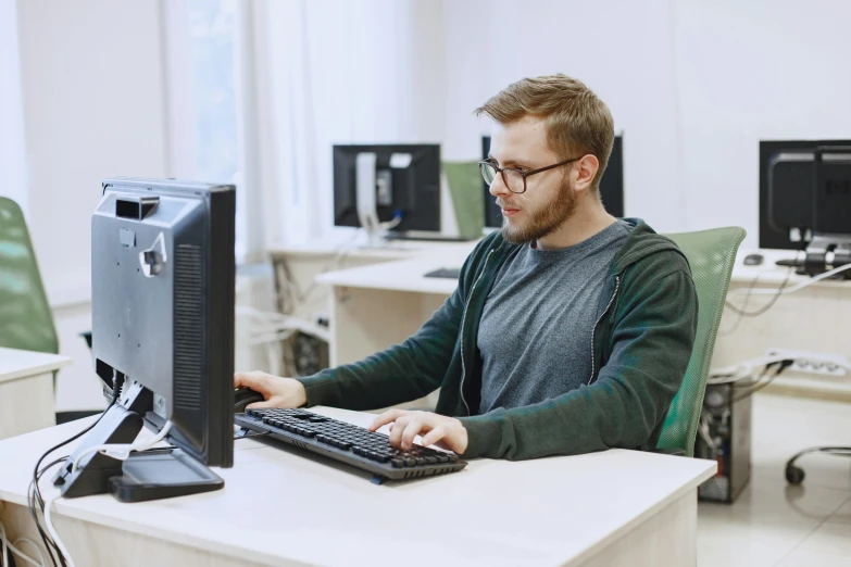 man in a gray shirt typing on a black keyboard