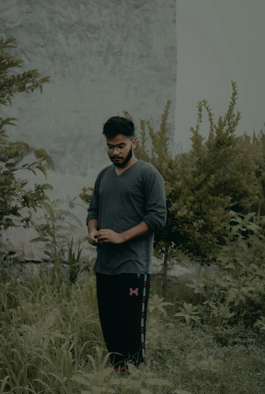 a man stands in the grass looking at his phone