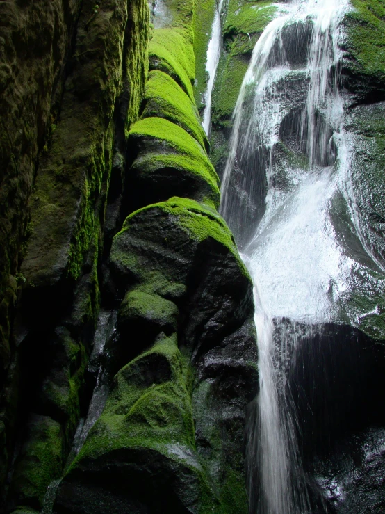 a waterfall in a rocky gorge with mossy rocks