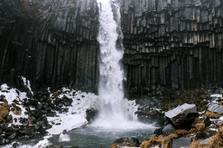 a waterfall in a rocky, snow covered landscape