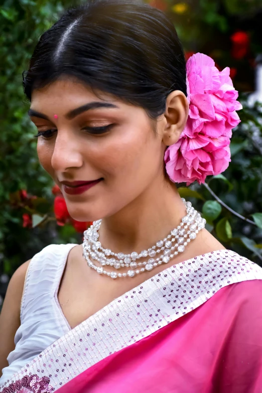 a woman wearing a pink flower and pearls necklace