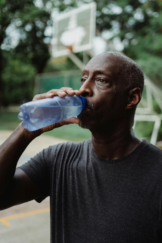 a man is drinking water from a blue bottle