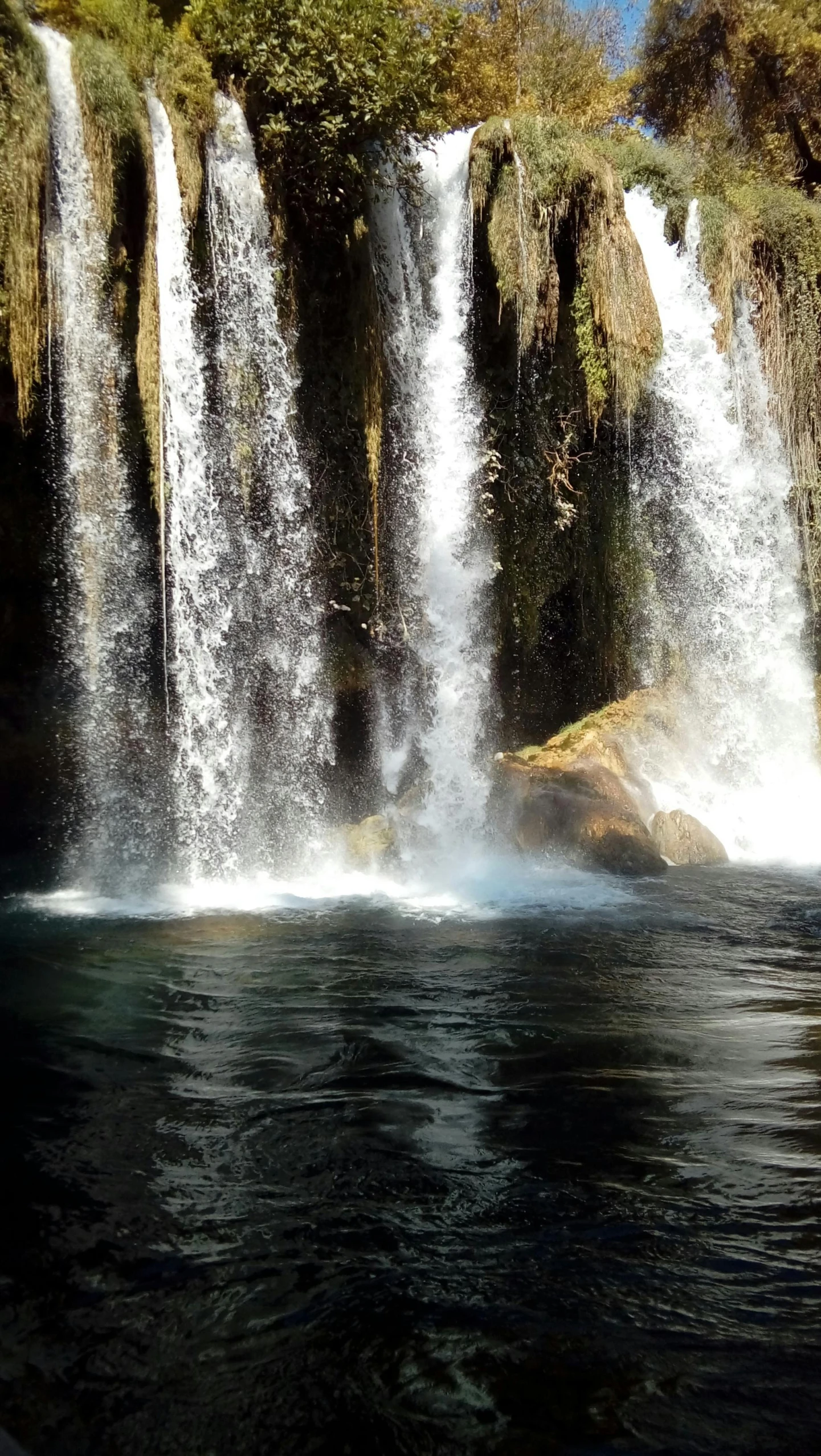 a large waterfall with a group of people standing in the water