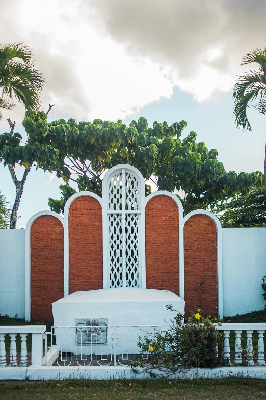 a brick and white structure and gate and trees