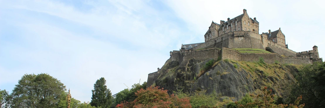 a castle sits on top of a hill in the middle of a park