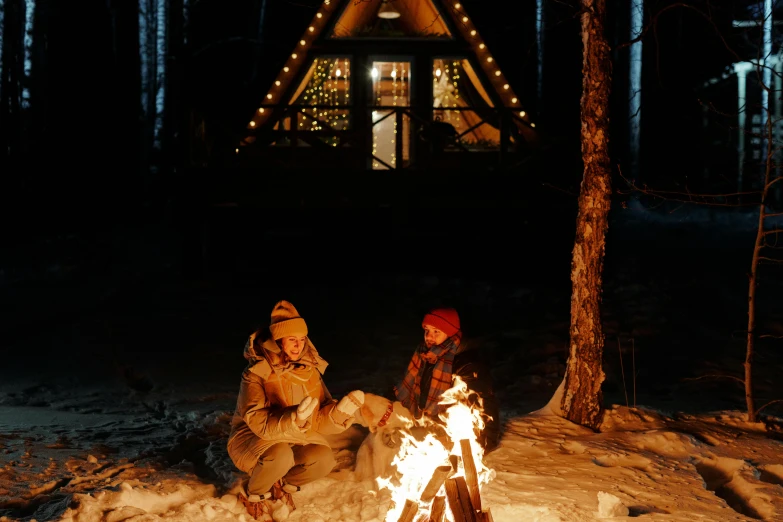 two people sitting around a campfire at night