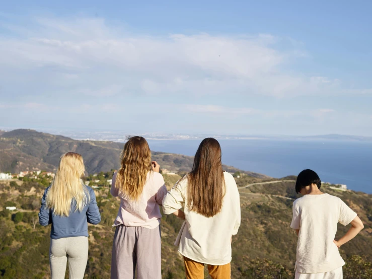 four woman overlooking an ocean and rolling hills