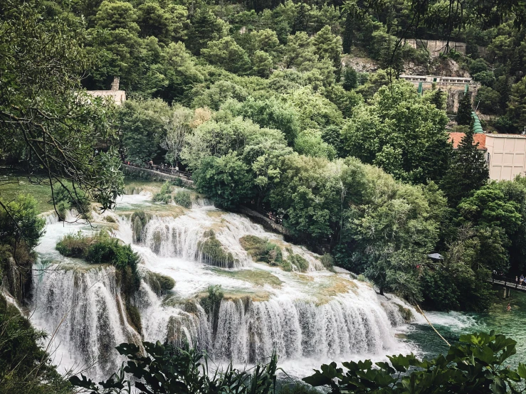 waterfall surrounded by trees next to trees and water