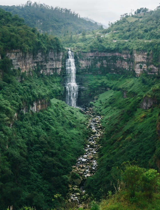 the waterfall is next to a rocky mountain