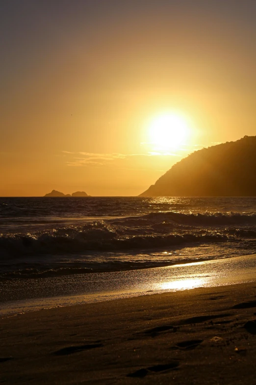 the sunset is shining over the ocean on a beach