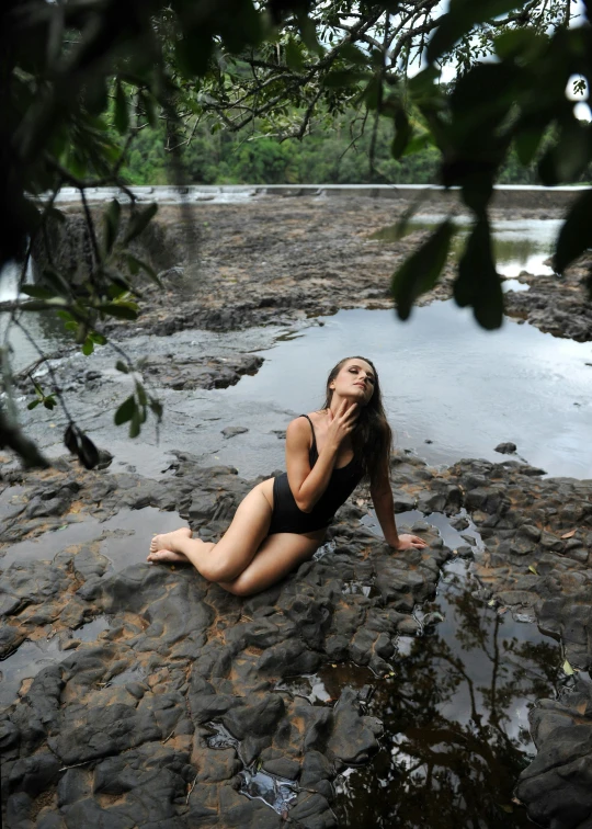 the woman is laying on the rocks by the water