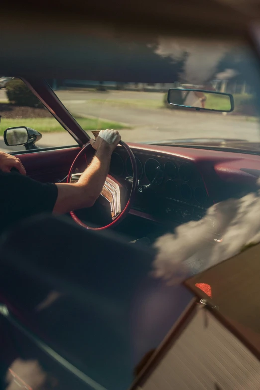 reflection in car mirror showing man holding steering wheel and driver's seat