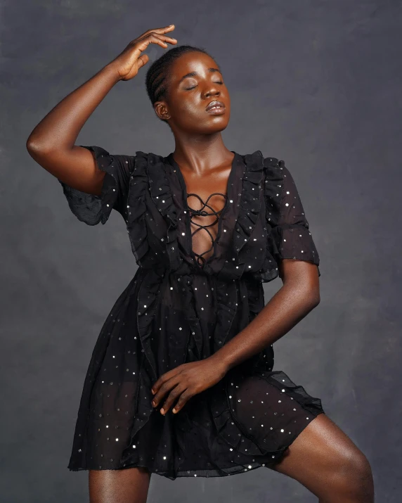 a beautiful young lady in a black dress with her arms up