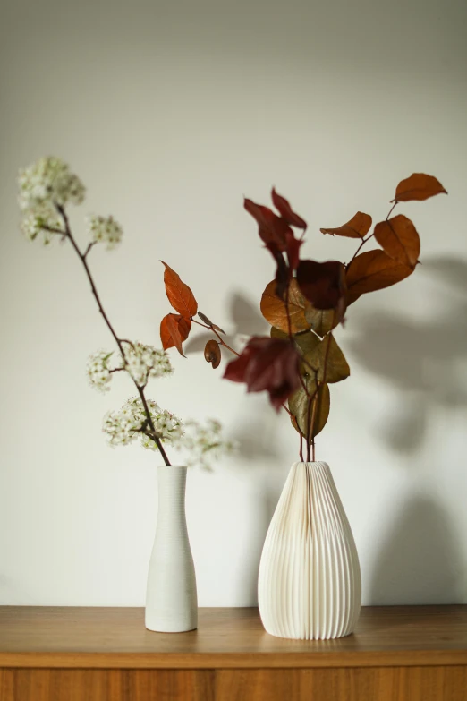 two white vases filled with colorful foliage