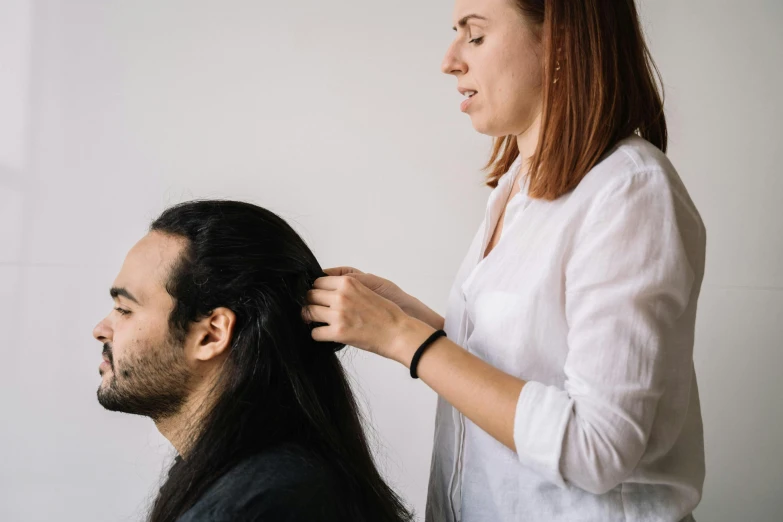 a woman straightening her long hair is standing next to a man