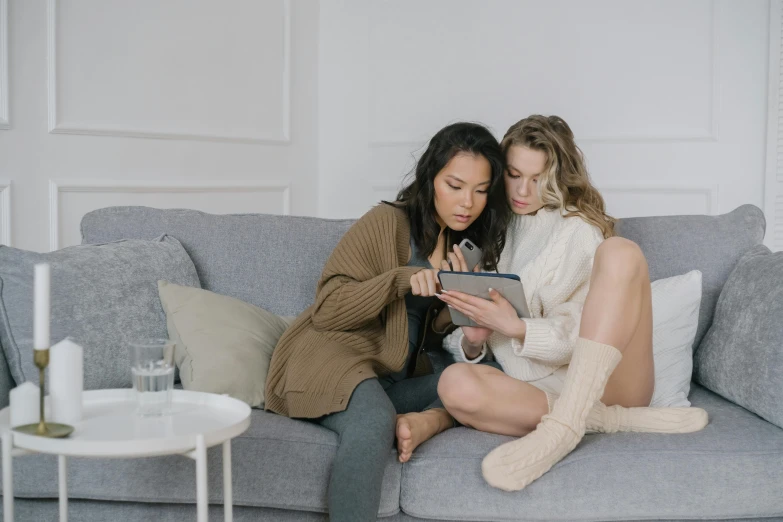 two women sitting on a couch in a living room