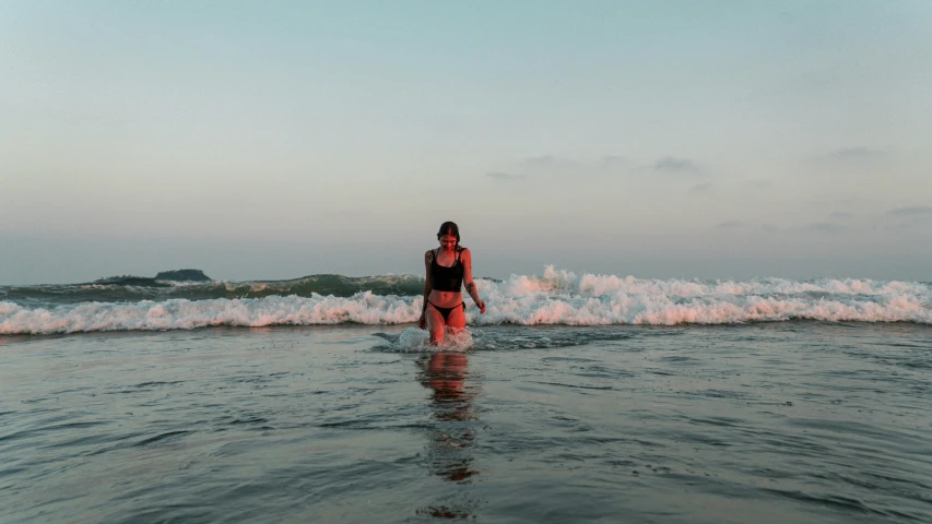 a woman walking into the ocean with a surfboard