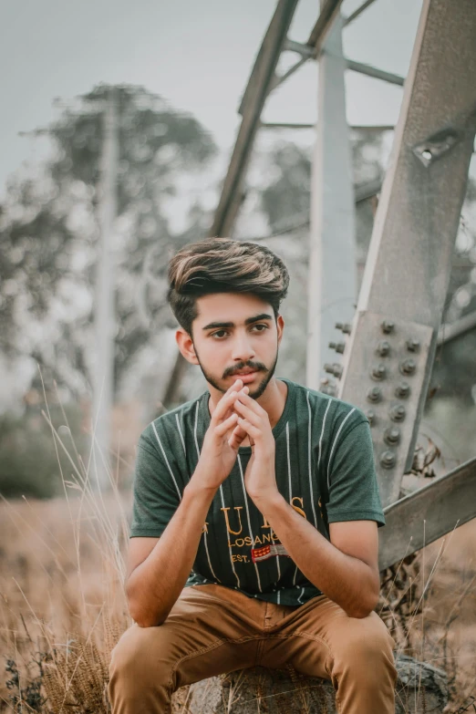 a man sits on a wooden log wearing a t - shirt