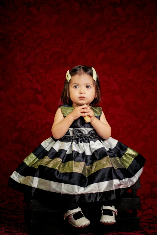 a  with her hands crossed while seated on a stool