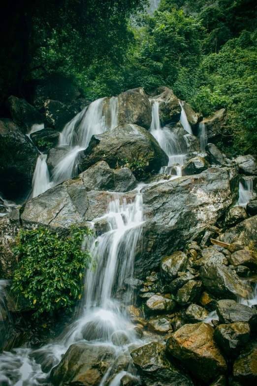 an outdoor waterfall has many large rocks