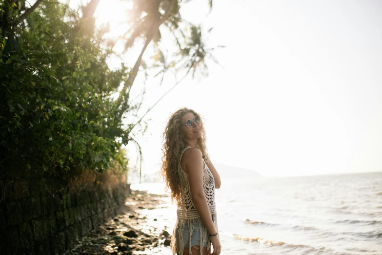 the woman is standing on a beach by the water