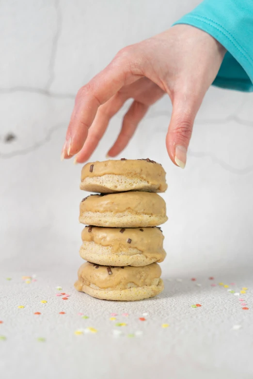 a person reaches for a stack of cookies with sprinkles