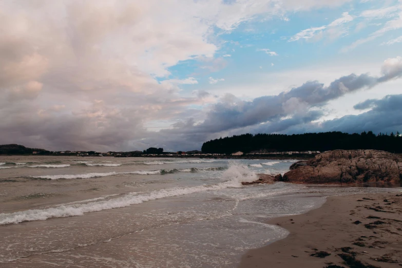 some sand water trees and clouds and some sand