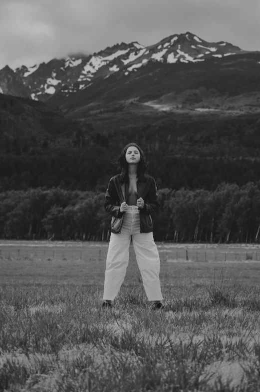 a woman posing for a po while in front of snow capped mountains