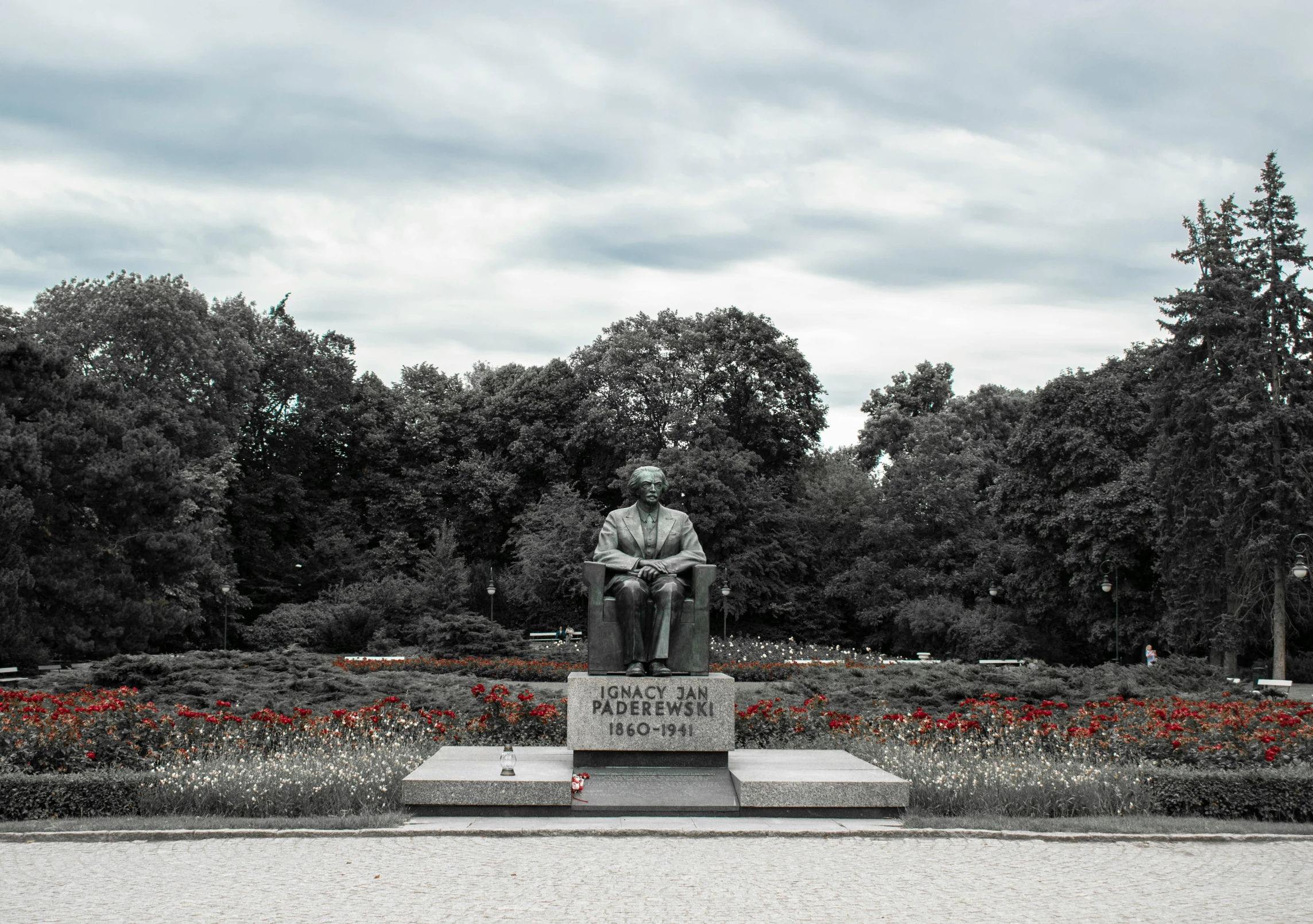 a statue sits in front of flowers in a park