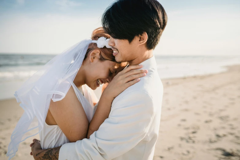 bride and groom on a beach emcing with ocean in the background