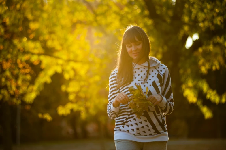 a woman in the sunlight holding plants