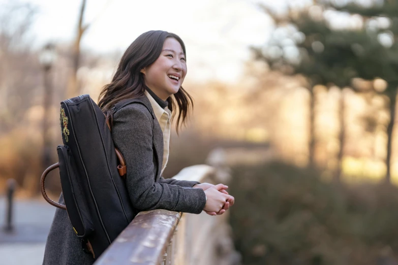 the young woman smiles while she walks beside a long wood railing