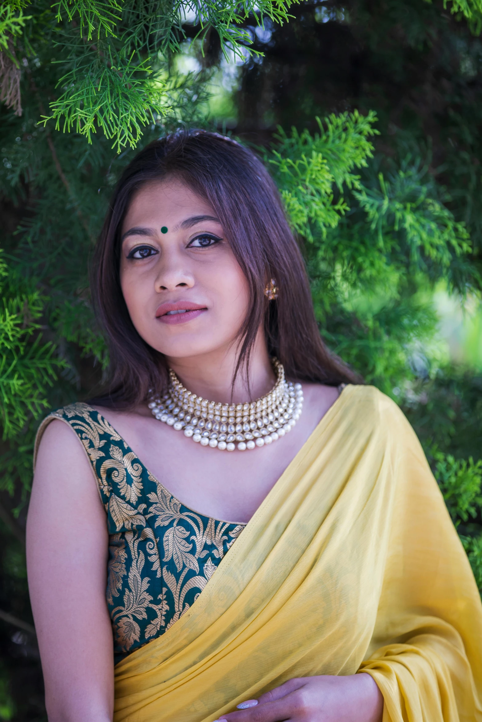 an attractive young lady posing in a saree and wearing a pearled necklace