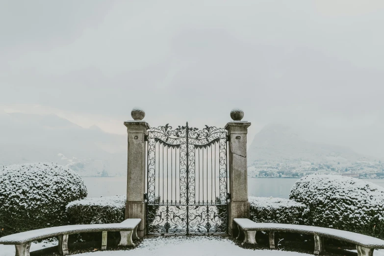 an elaborate gate covered in snow on top of a hill