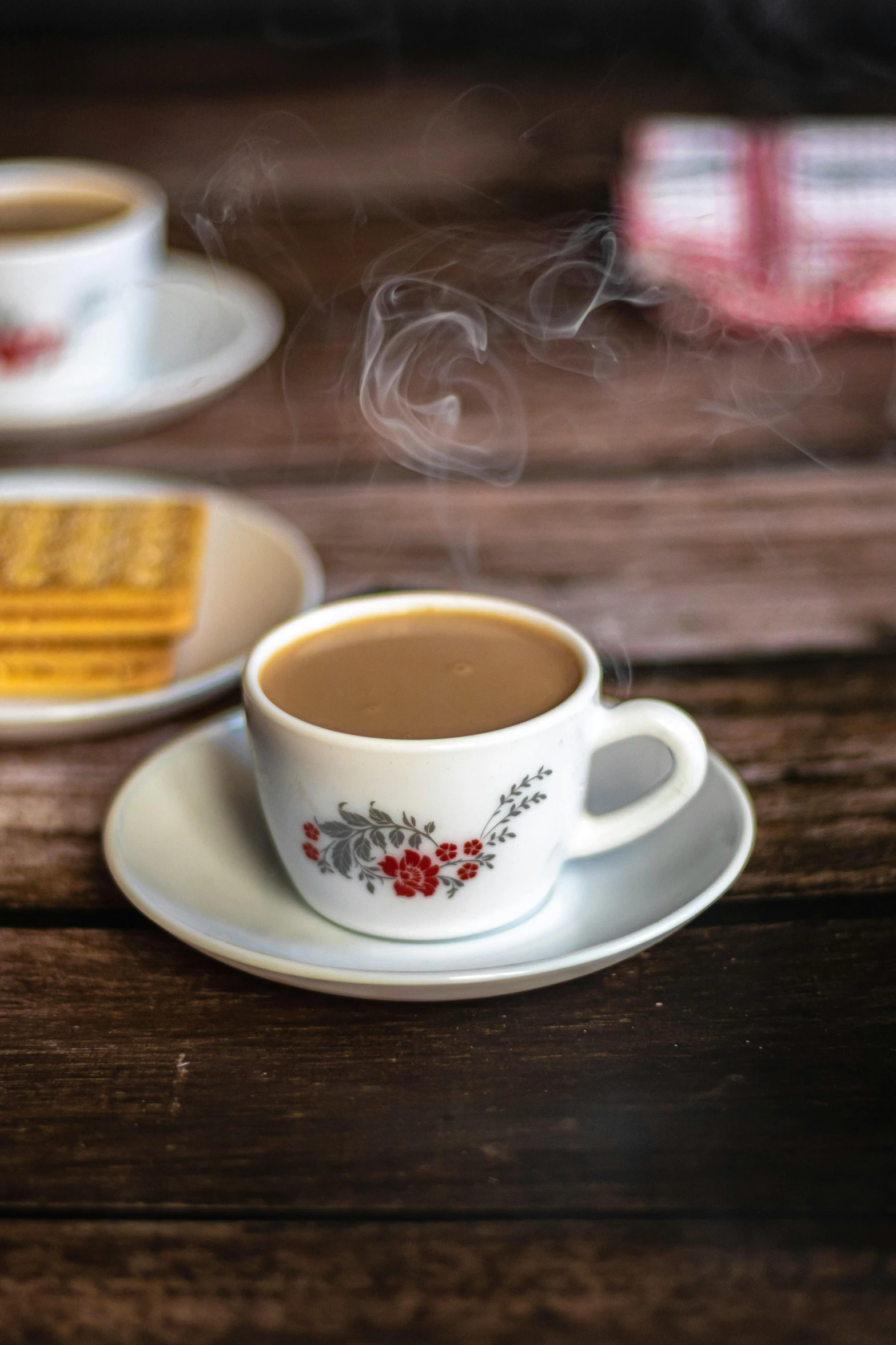 a  beverage sits in a white cup on a saucer next to two cookies